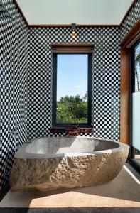 una gran bañera de piedra en una habitación con ventana en Garrya Bianti Yogyakarta en Yogyakarta
