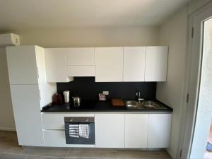 una cocina blanca con fregadero y armarios blancos en Appartamenti Villa Andrea, en Garda