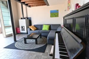 een woonkamer met een bank en een piano bij CA CENTOSA ARTISTIC HOUSE villa storica ristrutturata con patio e giardino in Cittadella