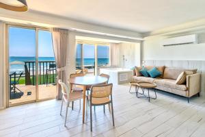 בית חוף מושלם עם גקוזי ומרפסת - Beachside Bliss W jacuzzi في حيفا: غرفة معيشة مع أريكة وطاولة وكراسي