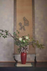 a red vase with flowers in it on a table at Aioi Yanto 一日一組限定古民家宿 in Otaru