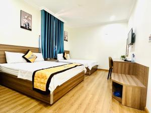 um quarto de hotel com duas camas e uma televisão em Hưng Nguyễn Hotel em Ha Long