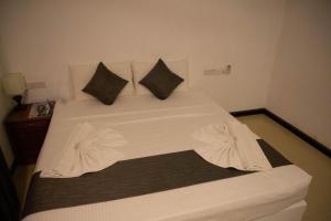 Una cama con sábanas blancas y almohadas. en CityRest Fort, en Colombo