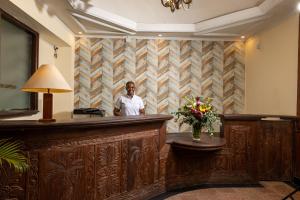 a man standing at a bar in a hotel lobby at Sentrim Castle Royal Hotel in Mombasa