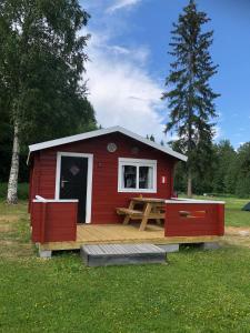 een rode hut met een houten terras in een veld bij 2/4 persoons stuga lyx in Hammarstrand