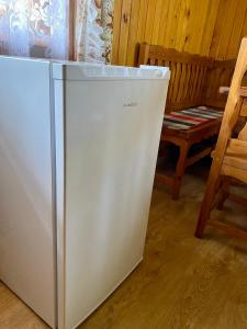 a white refrigerator in a room with a chair at Chatka Valaška in Terchová
