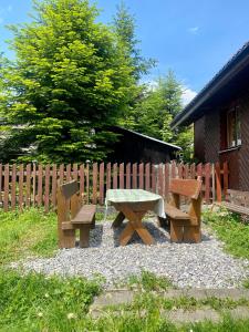 stół piknikowy i dwie ławki przed płotem w obiekcie Chatka Valaška w Tierchowej