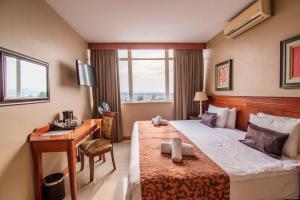 Cette chambre comprend un lit, un bureau et une fenêtre. dans l'établissement Emakhosini Hotel On East, à Durban