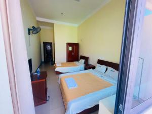 a hotel room with two beds and a television at BIDV HOTEL CỬA LÒ in Dong Quan