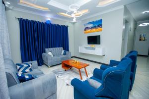 a living room with blue chairs and a table at Niwa Apartments in Dar es Salaam