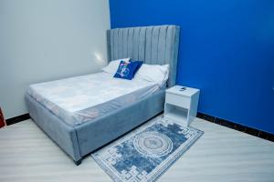 Cama pequeña en habitación con pared azul en Niwa Apartments, en Dar es Salaam