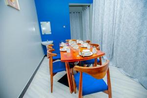 una mesa de madera y sillas con tazas y platos. en Niwa Apartments en Dar es Salaam