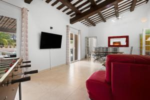 a living room with a red couch and a tv at Grande Villa entre Cannes St Tropez in Puget-sur Argens