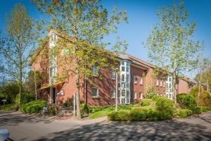 a red brick house with white windows on a street at LM5-17 - Ferienwohnung Typ AB Komfort in Schottwarden