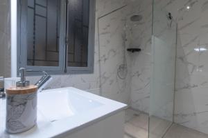 ein weißes Bad mit einem Waschbecken und einer Dusche in der Unterkunft Appartement moderne et élégant quartier Saint-Jean Perpignan in Perpignan