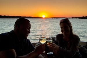 um homem e uma mulher sentados a uma mesa com copos de vinho em Room in Villa - Zambezi Family Lodge - Leopard Room em Victoria Falls
