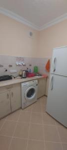 Il comprend une cuisine équipée d'un réfrigérateur blanc et d'un lave-linge. dans l'établissement 2-х комнатная квартира, à Balkhach