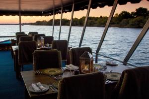 - une table à manger sur un bateau sur l'eau dans l'établissement Room in Villa - Zambezi Family Lodge - Leopard Room, à Victoria Falls