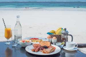 a table with a plate of breakfast food on the beach at Asha Boutique Hotel in Diani Beach