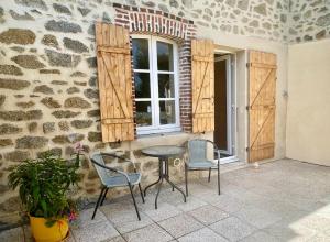 eine Terrasse mit 2 Stühlen, einem Tisch und einem Fenster in der Unterkunft La Petite Maison in Saint-Dizier-Leyrenne