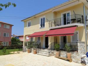 a large house with a red awning on it at Apartments Villa Ela in Umag