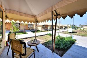 un patio con mesa, sillas y sombrilla en The Fern Seaside Luxurious Tent Resort Diu, en Diu