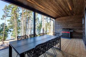 une salle à manger avec une table et des chaises sur une terrasse dans l'établissement Saunamäki Resort K - Luxury Designer Seafront Villa, à Salo