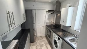 uma cozinha com armários brancos e uma máquina de lavar e secar roupa em CNTRL Reading Modernized 3 bedroom House em Reading