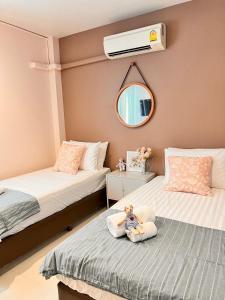 - une chambre avec 2 lits avec une poupée assise sur un oreiller dans l'établissement Por poshtel Kanchanaburi, à Kanchanaburi