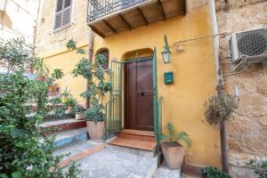 Casa amarilla con puerta de madera y escaleras en La Sedia Rossa Historical Centre, en Agrigento