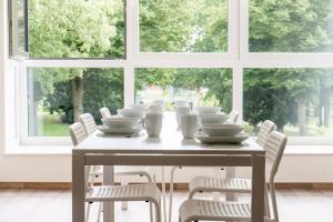 a table with white dishes and chairs in front of a window at Stay & Work - 6 single beds - central in Emmerich