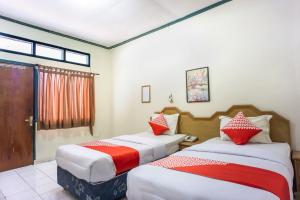 1 dormitorio con 2 camas y almohadas rojas y blancas en OYO 1636 Wisma Kuta Karang en Lhokseumawe