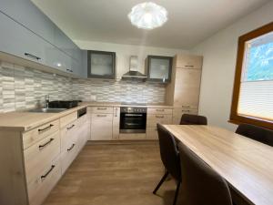 a kitchen with white cabinets and a wooden table at Karavanke Holiday Getaway in Hrušica