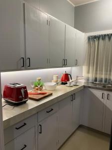 una cocina con armarios blancos y un aparato rojo en una encimera en The Cozy Hutt Home, en Upper Hutt