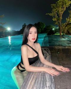 Eine Frau, die auf einem Surfbrett neben einem Pool sitzt. in der Unterkunft Moon Villa C27 Tam Đảo Golf & Resort Biệt thự 7 phòng ngủ rộng 1300m2 trong sân Golf Tam Đảo in Tam Ðảo