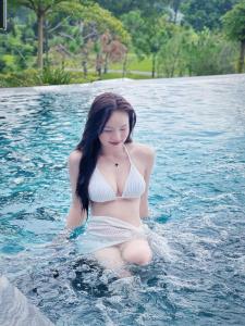 una mujer en bikini sentada en el agua en Moon Villa C27 Tam Đảo Golf & Resort Biệt thự 7 phòng ngủ rộng 1300m2 trong sân Golf Tam Đảo, en Tam Ðảo