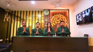 a group of four people wearing ties standing behind a table at Hotel Green Apple in Rourkela