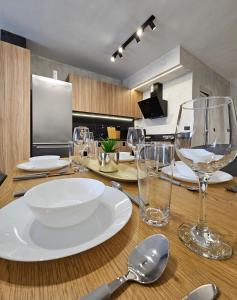 uma mesa de madeira com pratos e copos em Rea Home Apartment em Sófia