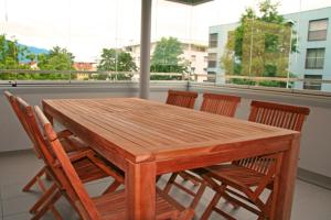 y balcón con mesa y sillas de madera. en Nest - Feldhof 5 en Zug