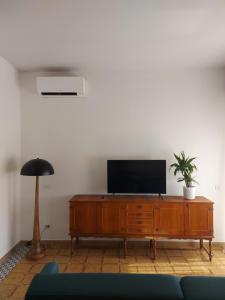 a living room with a television on a wooden cabinet at Santa Faustina Holy Apartment in Porto Ercole