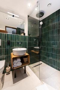 uma casa de banho com azulejos verdes, um lavatório e um chuveiro em The Barthels Boutique Hotel em Wurtzburgo