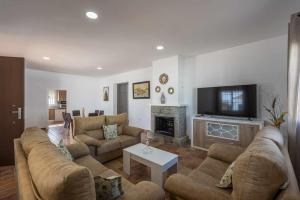 ein Wohnzimmer mit Sofas, Fernseher und Kamin in der Unterkunft Casa Rural Brisa del Valle in La Puebla de Cazalla