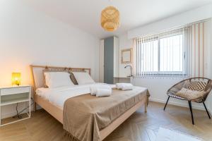 a bedroom with a large bed and a chair at Nathaniel - Appt terrasse 5 min de la plage in Arcachon