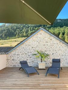 two chairs sitting on a wooden deck with a plant at Domaine des Combes - La Ferme aux Anes 14 pers. in Millau