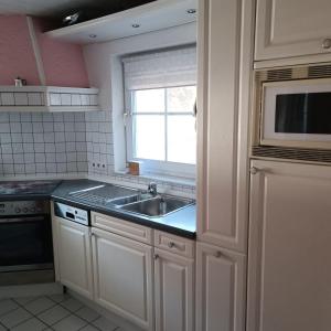 eine Küche mit einem Waschbecken und einem Fenster darin in der Unterkunft Ferienwohnung Gogelhopf EG in Unterschneidheim