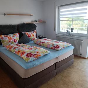 1 Schlafzimmer mit 2 Betten und bunten Kissen in der Unterkunft Ferienwohnung Gogelhopf EG in Unterschneidheim