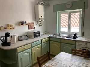 a kitchen with green cabinets and a sink and a table at Terraço do Lima in Ponte de Lima