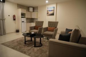 uma sala de estar com um sofá, cadeiras e uma mesa em فندق رحيب للشقق المخدومة Rahib Suites em Abha