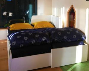 a white bed with yellow pillows on top of it at La Petite Maison du hÊtre in Brassac