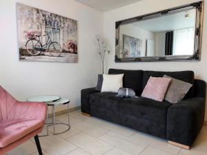 Pension Waldblick في هايدنهايم آن دير برينز: غرفة معيشة مع أريكة سوداء ومرآة